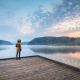 Person standing on a pier staring at the sunset over water