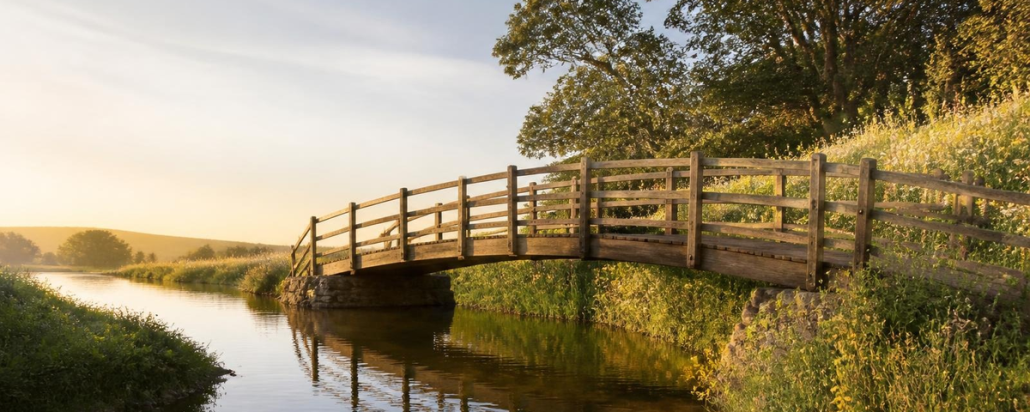 Wooden footbridge over a calm stream at golden hour